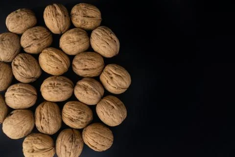 Walnuts in shell on black surface, top view. Background of round walnuts Stock Photos