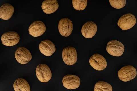 Walnuts in the shell on black surface, top view. Background of round walnuts Stock Photos