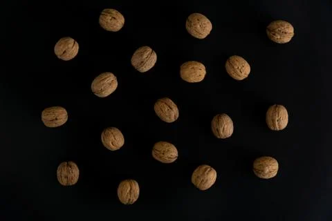 Walnuts in the shell on black surface, top view. Background of round walnuts Stock Photos