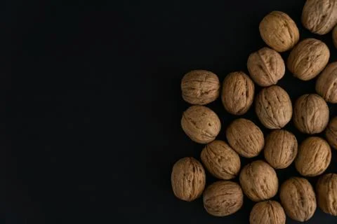 Walnuts in the shell on black surface, top view. Background of round walnuts Stock Photos