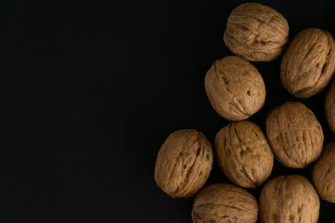 Walnuts in the shell on black surface, top view. Background of round walnuts Stock Photos