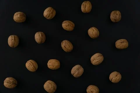 Walnuts in the shell on black surface, top view. Background of round walnuts Stock Photos