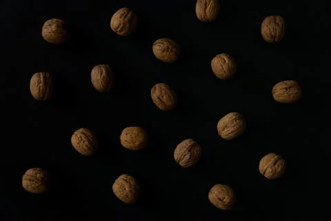 Walnuts in the shell on black surface, top view. Background of round walnuts Stock Photos