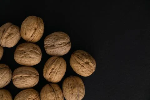 Walnuts in the shell on black surface, top view. Background of round walnuts Stock Photos