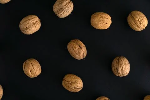 Walnuts in the shell on black surface, top view. Background of round walnuts Stock Photos