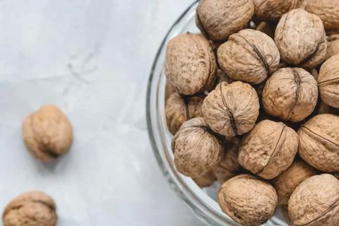 Walnuts in shell in bowl on gray background Stock Photos