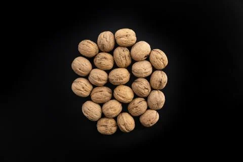 Walnuts in shell in the center on black surface, top view. Background of round Stock Photos