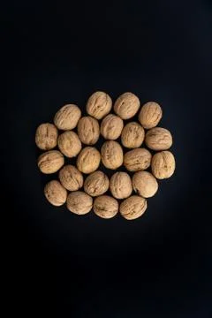 Walnuts in shell in the center on black surface, top view. Background of round Stock Photos