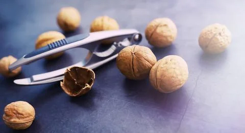 Walnuts in a shell on a gray background. Nutcracker and scattering of nuts. Foto stock