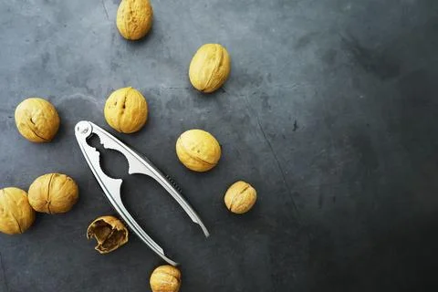 Walnuts in a shell on a gray background. Nutcracker and scattering of nuts. Foto stock