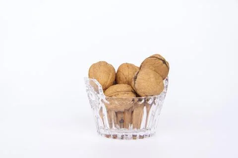 Walnuts in a shell on a white background in a crystal vase. Healthy nuts. Stock Photos