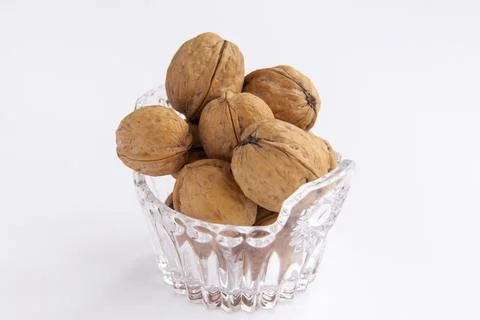 Walnuts in a shell on a white background in a crystal vase. Healthy nuts. Stock Photos