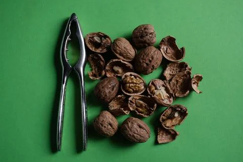 Walnuts, Shells and Silver Nutcracker on Green Background Stock Photos