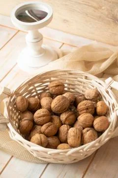 Walnuts with shells in white basket. Vertical image Stock Photos