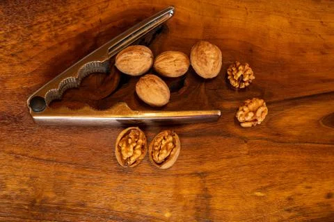 Walnuts with silver nutcracker on wooden background. It originated from a cro Stock Photos