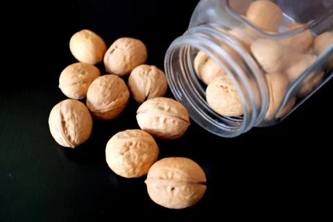 Walnuts spilled from a can on a black table Stock Photos