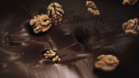 Walnuts Splashing Into Liquid Dark Chocolate in 4K Super slow motion Stock Footage 141079296