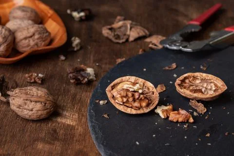 Walnuts on a stone plate next to a nutcracker. Close-up. Stock Photos