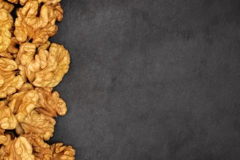 Walnuts. Walnut kernels on dark black stone background. Top view, flat lay Stock Photos
