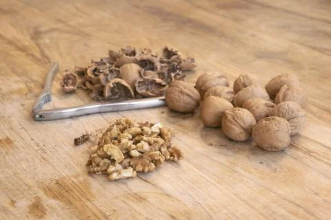 Walnuts whole and cracked with shells and nutcracker on wooden cutting board Stockfoto's