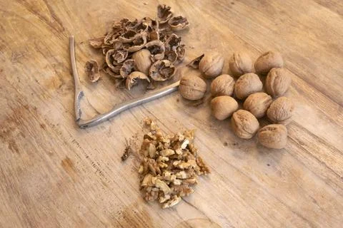 Walnuts whole and cracked with shells and nutcracker on wooden cutting board Stockfoto's