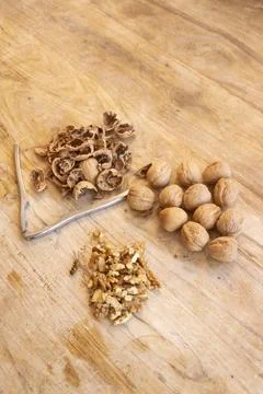 Walnuts whole and cracked with shells and nutcracker on wooden cutting board Stockfoto's