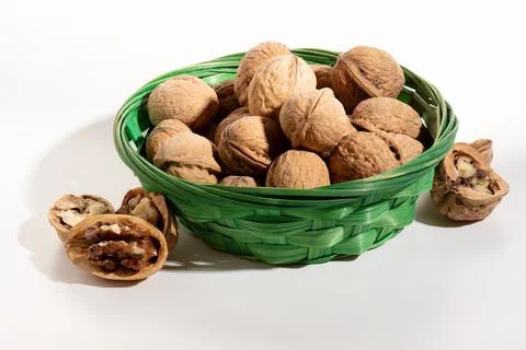 Walnuts in a wicker basket and split nuts isolated on a white background with Stock Photos