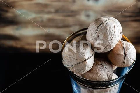 Walnuts in a wine glass. On a wooden background. On a dark wet table. Stock Photos