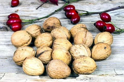 Walnuts witk rose hips on an old wooden table Stock Photos