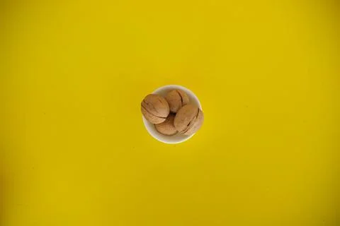 Walnuts on a yellow solid background. Food background. Kitchen. white plate Stock Photos