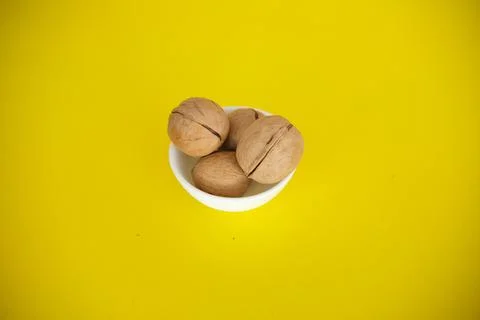 Walnuts on a yellow solid background. Food background. Kitchen. white plate Stock Photos