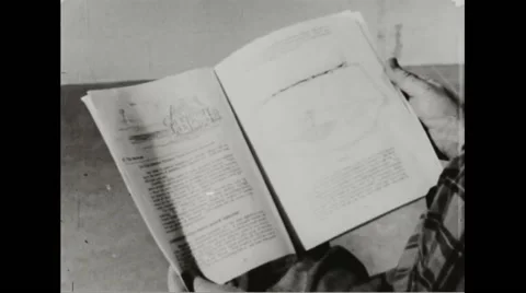 Walter Durbahn going through pages of guide book of The Family Fallout Shelter Stock Footage 44572133