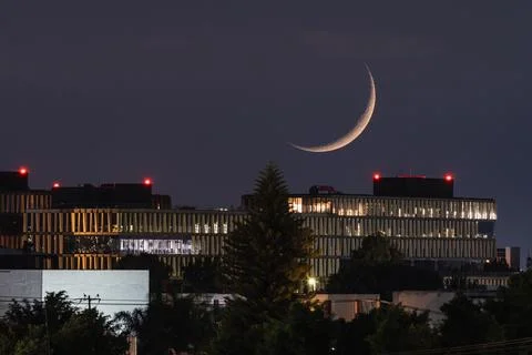 Waning Crescent Moon setting over urban cityscape after dusk Fotos Stock