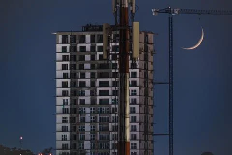 Waning Crescent Moon setting over urban cityscape after dusk Fotos Stock
