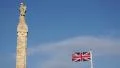 War memorial in Douglas, Isle of Man with British flag waving in front of it HD Footage