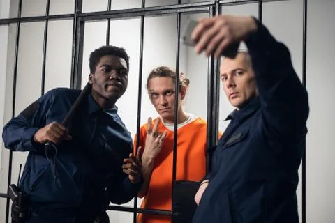 Wardens in a maximum security prison take selfies with a prisoner with tattoos Stock Photos