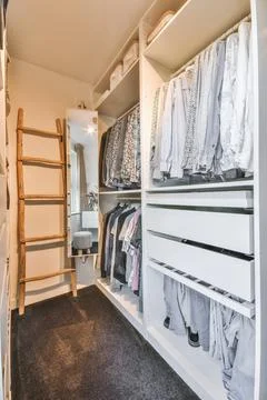 Wardrobe with assorted clothes in narrow dressing room Stock Photos