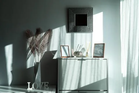 Wardrobe with some frames, a mirror and a vase with spikes in a white room Stock Photos