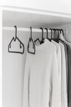 Wardrobe with sweaters on hangers Stock Photos