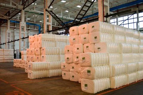 Warehouse with a bunch of huge, white, rectangular bags with acrylic fiber. Stock Photos