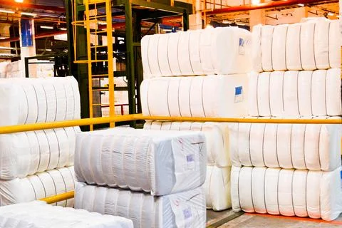 Warehouse with a bunch of huge, white, rectangular bags with acrylic fiber. Stock Photos