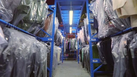 Warehouse with clothes. The clothes are hung in rows in the warehouse. Clothes Видео 196109987