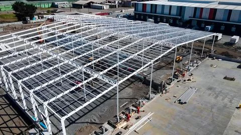 Warehouse construction process with metal structures and roofs Stock Photos