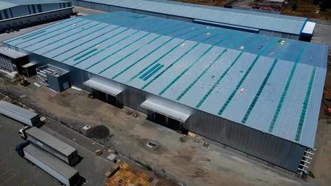 Warehouse construction process with metal structures and roofs Stock Photos