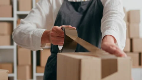 Warehouse delivery service packing boxes with tape, preparing parcel cardboa Stock Footage 218619718