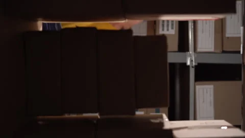 Warehouse elderly worker collects cardboard boxes and parcels of the shelf and Stock Footage 248592391