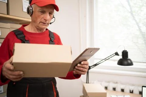 Warehouse employee in e-commerce delivery service using tablet and headset .. Stock Photos