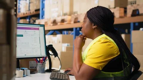 Warehouse employee using package tracking software on computer monitor Stock Photos