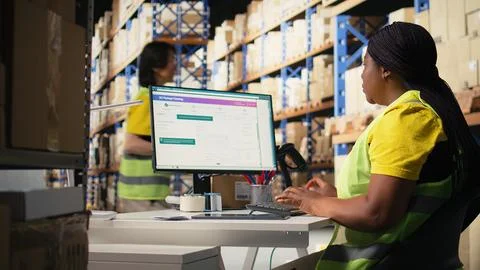 Warehouse employee using package tracking software on computer monitor Foto stock