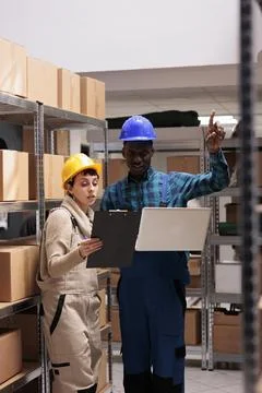 Warehouse employees comparing inventory data on clipboard and laptop Foto stock